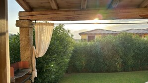 Un espacio al aire libre techado con un pérgola, una mesa pequeña y una silla.