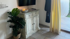 Una habitación con televisión en un mueble, un reloj en la pared y una planta.