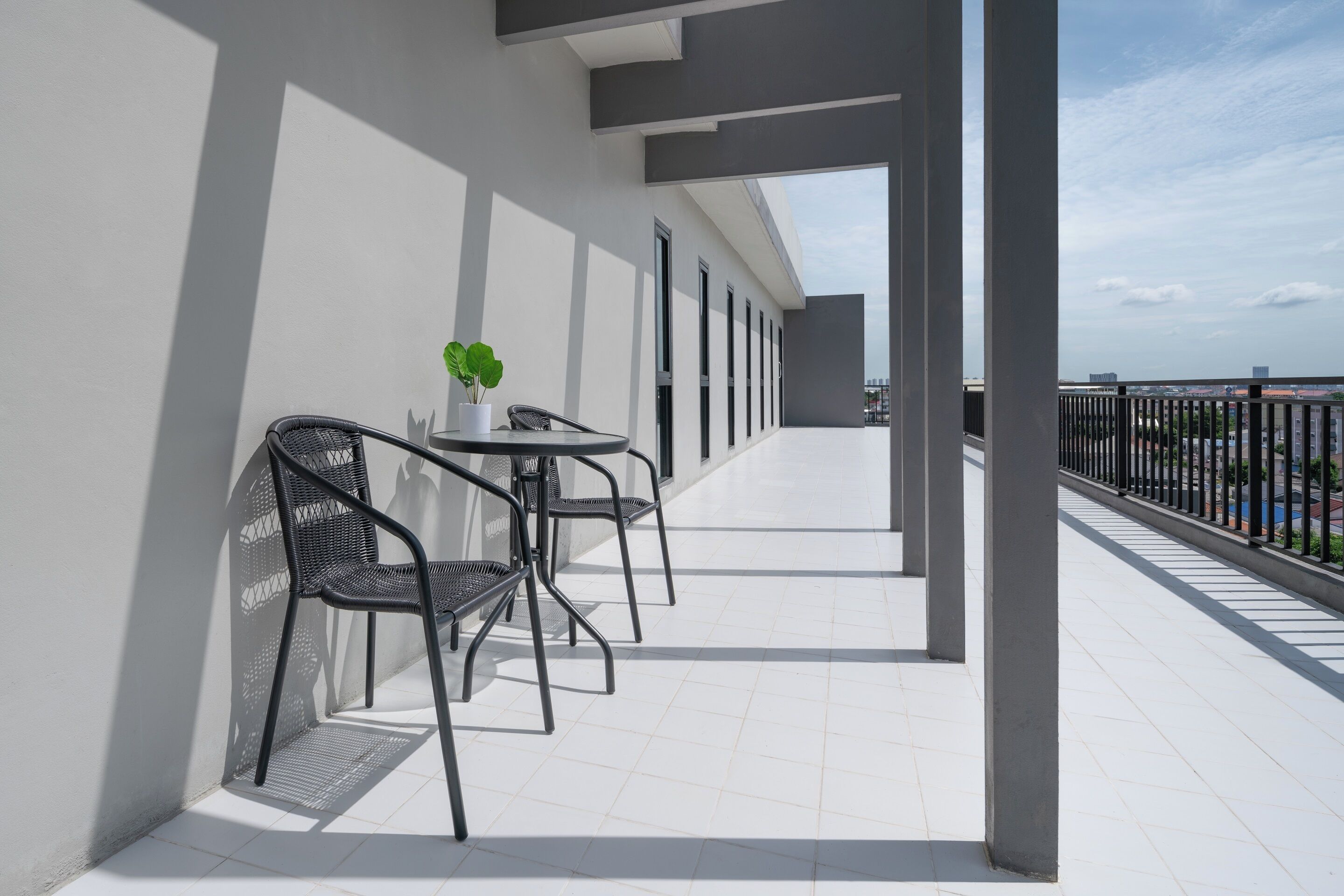 Un balcón con mesa y sillas, una planta en maceta y vistas de la ciudad.