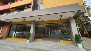 A modern hotel with a yellow and grey facade, large glass windows, and a visible entrance. - TRAVELITE EXPRESS HOTEL LA UNION (San Fernando)