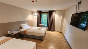 A hotel room with two beds, a TV, a small table, and a window with curtains. - TRAVELITE EXPRESS HOTEL LA UNION (San Fernando)