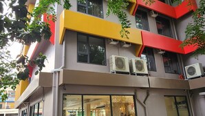 A multi-story building with a modern design, featuring a mix of yellow and red accents, large windows, and air conditioning units on the exterior. - TRAVELITE EXPRESS HOTEL LA UNION (San Fernando)