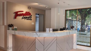 A reception desk with a 'Travellite Express Hotel' sign, a potted plant, and a laptop. - TRAVELITE EXPRESS HOTEL LA UNION (San Fernando)
