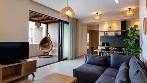 Una sala de estar moderna con una televisión de pantalla plana, una mesa de centro de madera y un sofá gris.