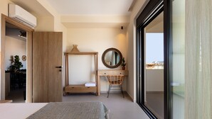 Un dormitorio con cama, escritorio, silla, espejo y puerta corrediza de cristal a un balcón.