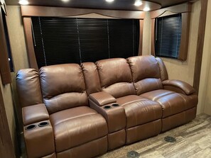 Relax on the comfortable leather sofa with a console table and cup holders.