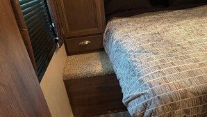 A bedroom with a bed, a wooden cabinet, and a carpeted floor. - Motorized Lake Front property. (Wasilla)