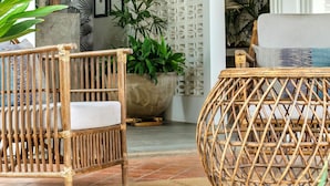 A room with wicker furniture, a large potted plant, and a decorative wall panel.