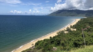 A coastal landscape with a beach, ocean, and mountains in the background. - Romantic rainforest retreat with magical waterfall (Cow Bay)