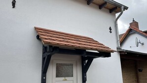 A white building with a brown tiled roof, a white door, and a small window. - Kutscherhaus / Stadthaus Usedom (Usedom)