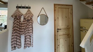 A room with a wooden ceiling, a hanging light fixture, a mirror, a wooden door, and a tiled floor. - Kutscherhaus / Stadthaus Usedom (Usedom)
