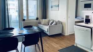 A compact living space with a dining area, a sofa, a coffee machine, and a view through a window. - Completely new designer apartment on the ground floor with a spacious patio (Espoo)