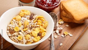 A bowl of cereal with toast and jam on a wooden table. - Woody Crest Hotel (Trincomalee)