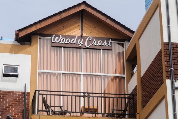 Un edificio con un letrero que dice 'Woody Crest' y un balcón con barandilla.