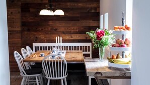 A wooden dining table with white chairs, a bench, and a fruit display. - Hiša Poljana (Prevalje)