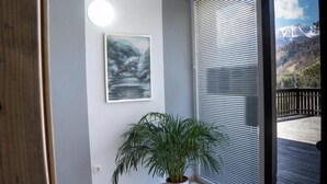 A room with a large window, a potted plant, and a painting on the wall. - Hiša Poljana (Prevalje)