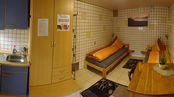Une petite pièce comprenant un lit, une petite table, un lavabo et un placard.