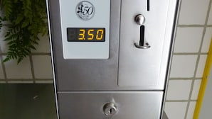 Ett kassaskåp av metall med en digital display som visar siffran ”3,50” och ett låsmekanism.