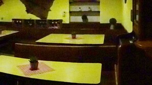 Un restaurante con cabinas y mesas, piso de baldosas y una pared amarilla.