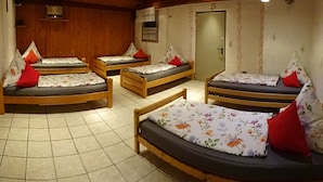 Una habitación con cuatro camas de madera, cada una con ropa de cama floral y almohadas rojas.