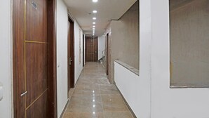 A hallway with wooden doors, a tiled floor, and a staircase at the end. - Hotel Fortune Stay (Ghaziabad)