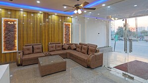 A modern lobby with a sectional sofa, a coffee table, and a ceiling fan. - Hotel Fortune Stay (Ghaziabad)