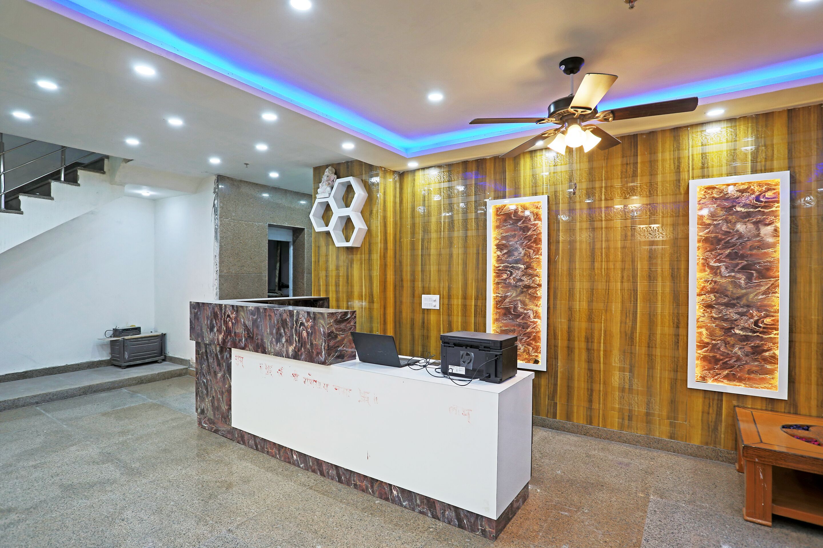 A reception area with a marble counter, a ceiling fan, and a staircase.