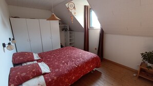 Quarto com cama, guarda-roupa e uma pequena planta.