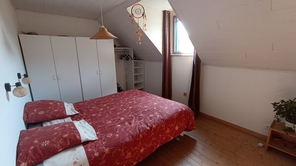 Une chambre à coucher avec un lit, une armoire et une petite plante.
