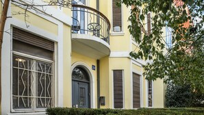 Un bâtiment jaune doté d’un balcon, d’une grande fenêtre ornée de barreaux en métal et d’une porte en arc de cercle.