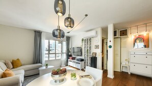 Un salon moderne avec une table à manger, un canapé et un téléviseur. On y trouve également une bibliothèque et un meuble blanc.