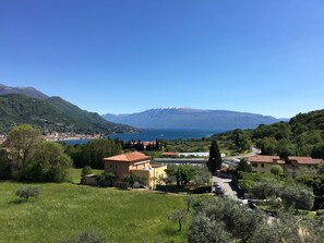 Vista de uma vila costeira com um lago, montanhas ao fundo e uma mistura de edifícios residenciais e comerciais.