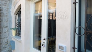 A building entrance with a white door, a small window with a potted plant, and a wall-mounted mailbox. - Casa Priscilla (Salò)