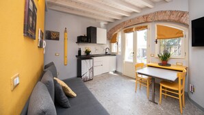 A compact living space with a kitchenette, a dining area, and a sofa. - Casa Priscilla (Salò)