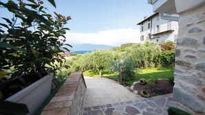 A stone pathway leading to a lush garden with a view of mountains in the distance. - Casa Priscilla (Salò)