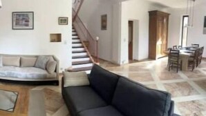 Een woonkamer met een bank, een salontafel, een open haard en een trap naar een andere kamer.