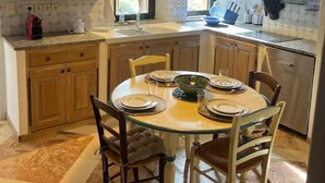 Een keuken met houten kastjes, een eettafel voor vier personen en een hangende lamp.