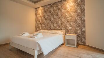 Un dormitorio moderno con cama, mesita de noche y pared con diseño de hojas.