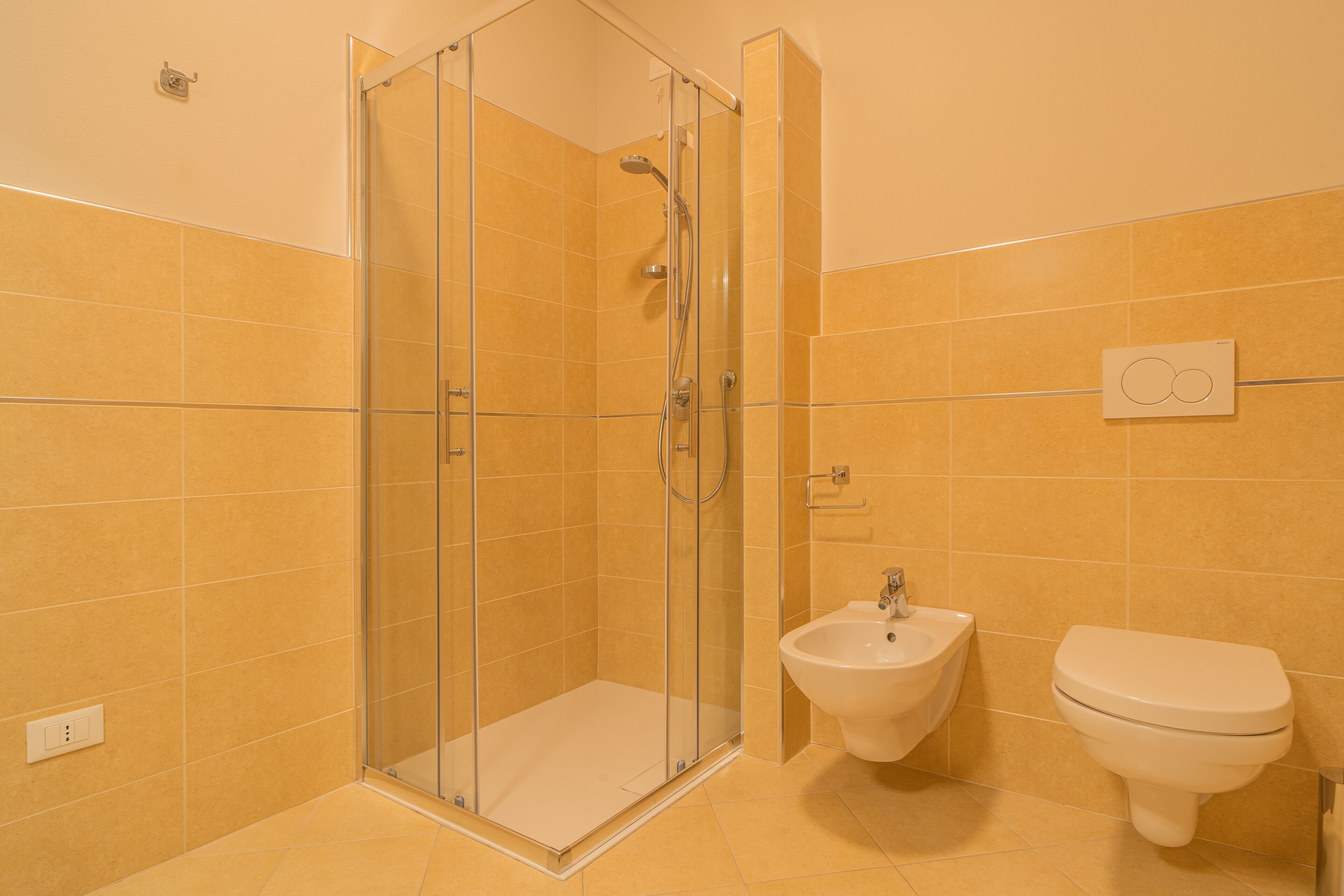 Un baño con ducha envuelta en vidrio, un bidé y un inodoro.