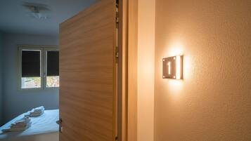 A room with a bed, a door, and a wall-mounted light fixture.