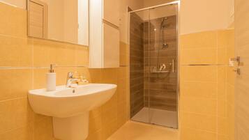 A bathroom with a sink, mirror, and glass-enclosed shower.
