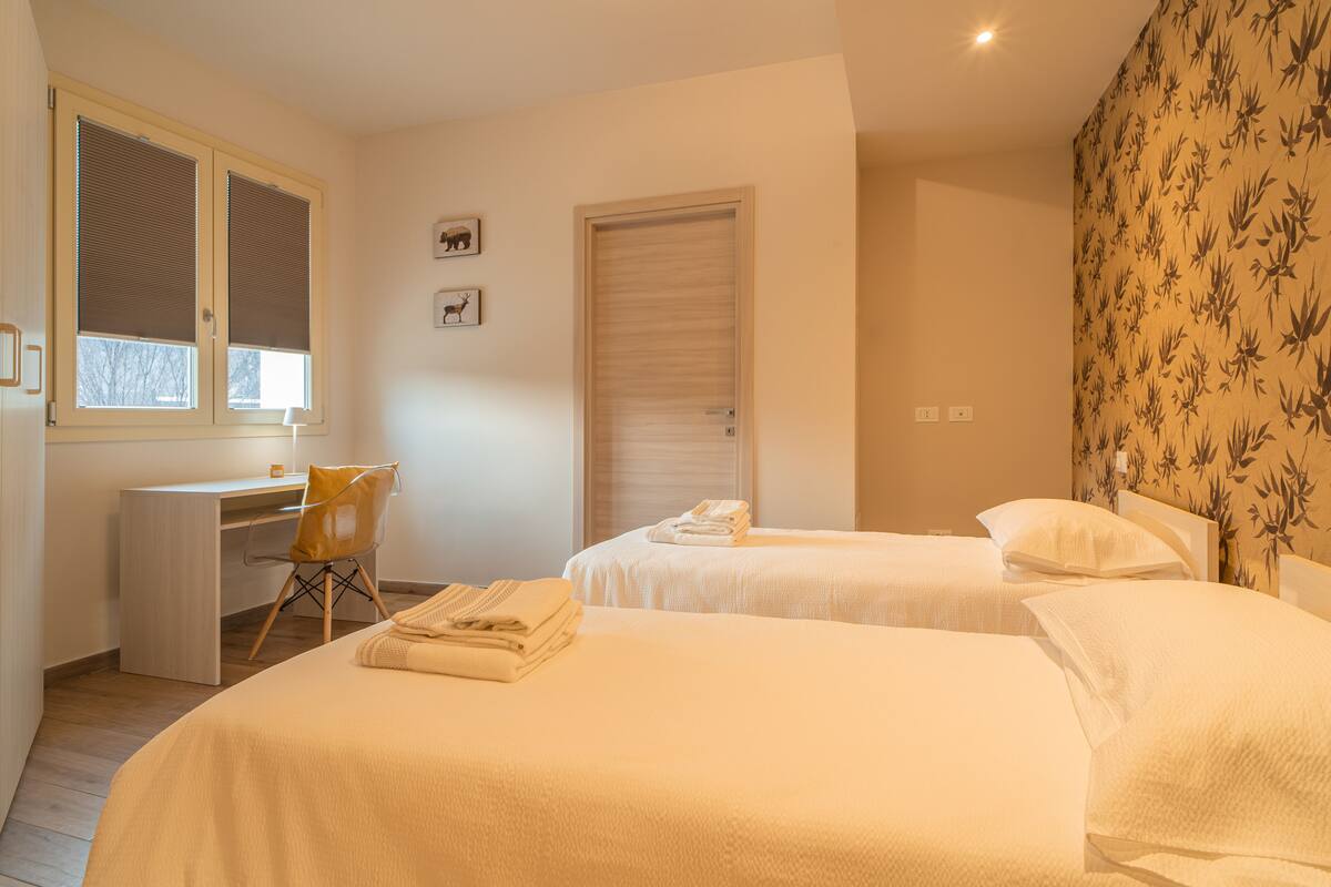 A hotel room with two beds, a desk, and a chair.