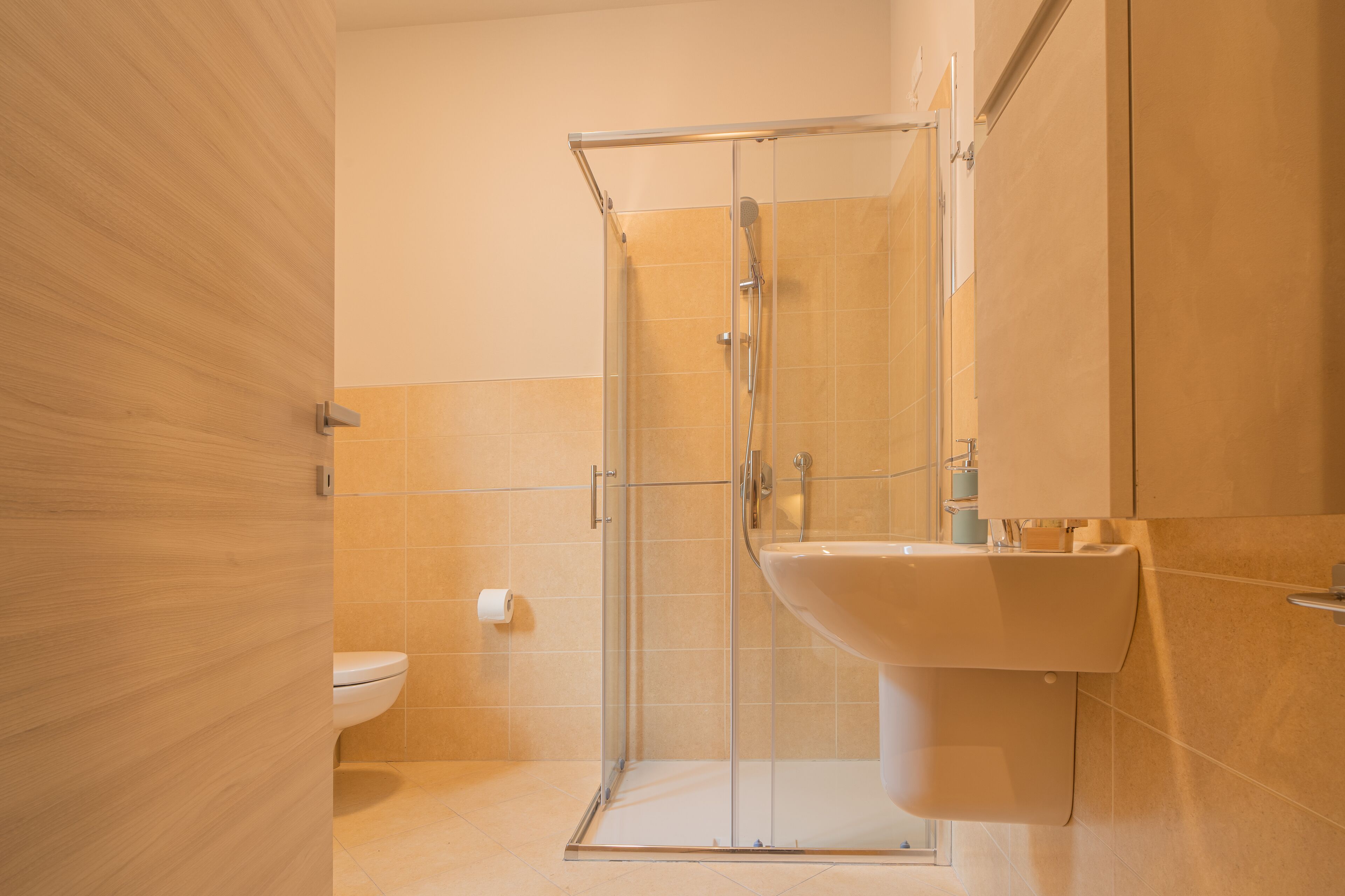 Une salle de bain moderne avec une douche à parois de verre, un lavabo blanc et des toilettes.