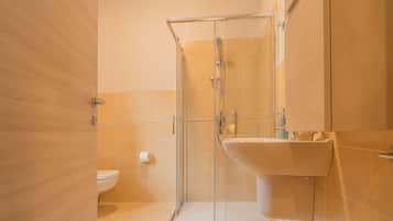 Une salle de bain moderne avec une douche à parois de verre, un lavabo blanc et des toilettes.