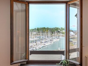 Une baie où de nombreux bateaux sont amarrés, un ciel dégagé et une vue sur une ville au loin.