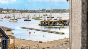 A marina with multiple boats docked, a wooden pier, and a building with a sign. - Le Quai by Interhome (La Trinité Sur Mer)
