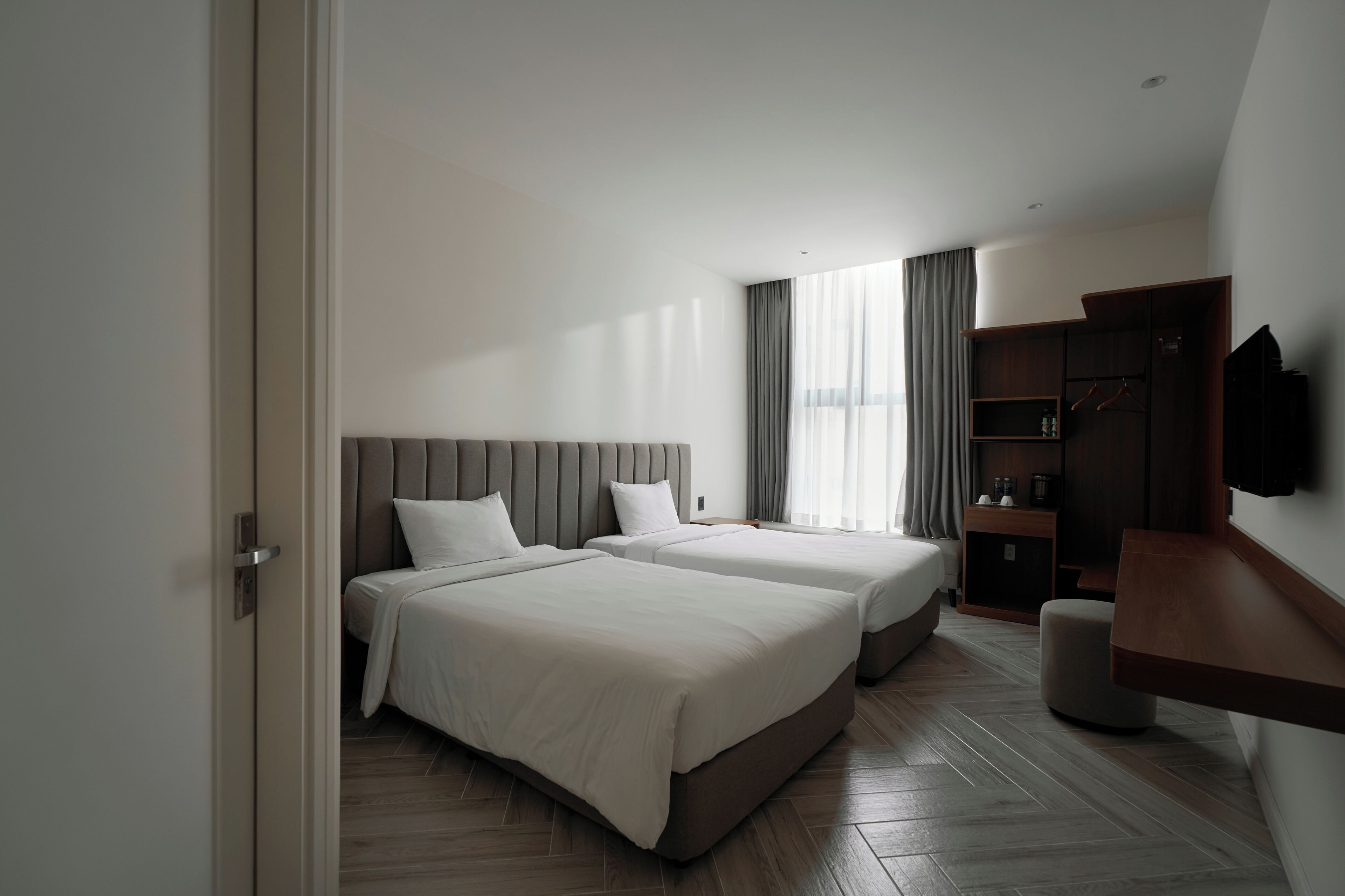 A hotel room with two beds, a TV, a desk, and a wardrobe.