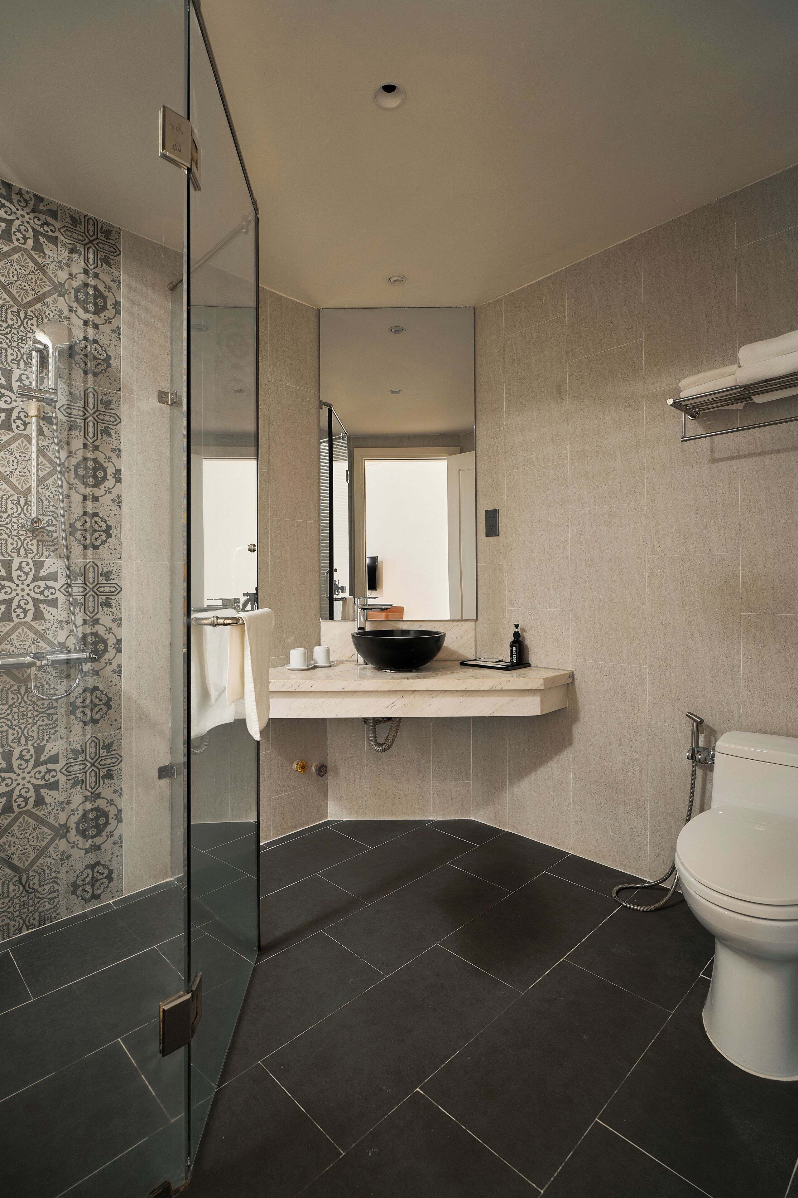 A modern bathroom with a glass shower enclosure, a white toilet, and a vanity with a black sink.