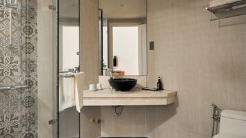 A modern bathroom with a glass shower enclosure, a white toilet, and a vanity with a black sink.