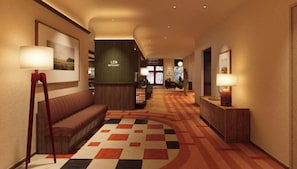 A hotel lobby with a reception desk, a sofa, a patterned carpet, and a wall-mounted sign. - Len Hotel (Da Lat)